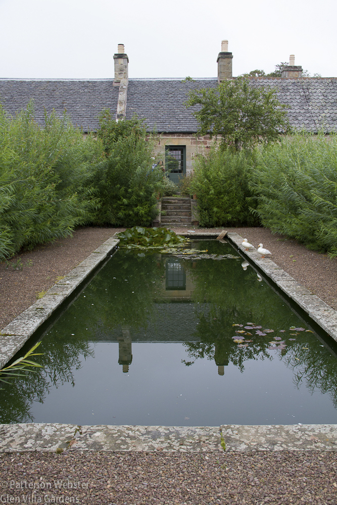 The willow pond reflects the farm buildings and the ever-present grey sky.