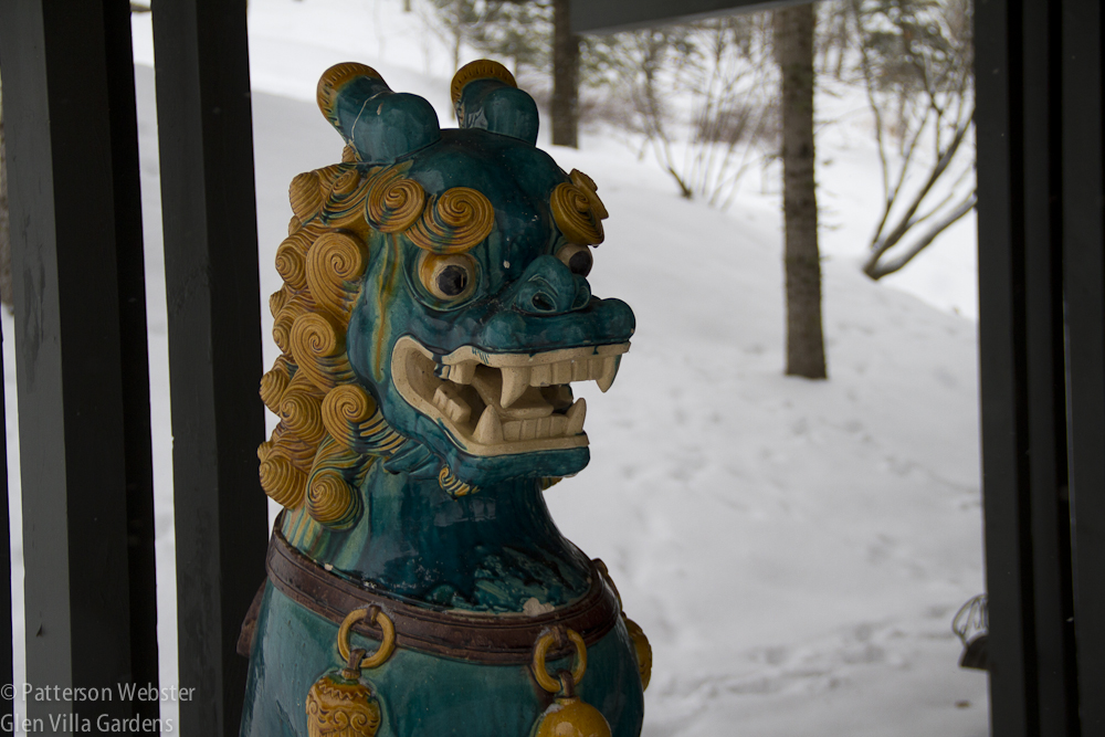 The lions stand guard under an overhanging roof, out of the way of snow.