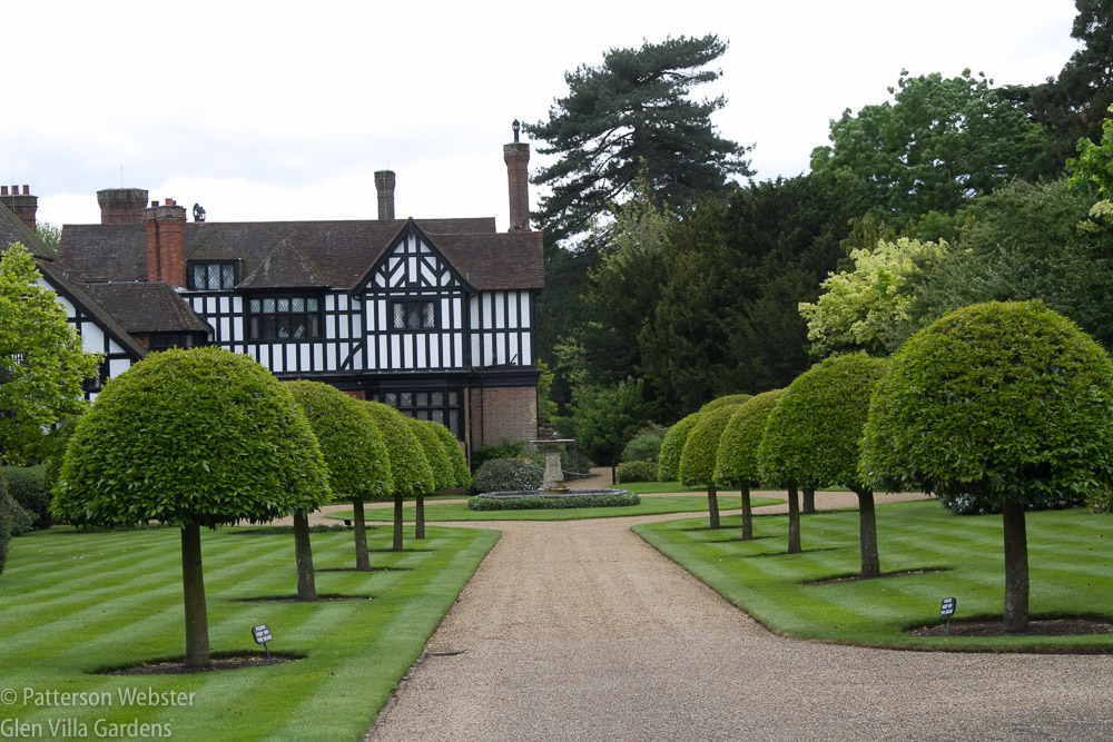 Formally clipped trees line a perfectly edged walkway in front of Ascott house.