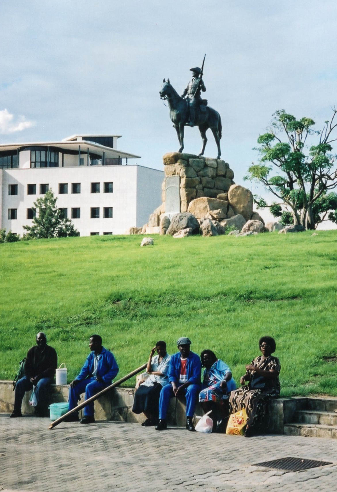 Do the people sitting on the curb in front of this statue know who the man on horseback was?