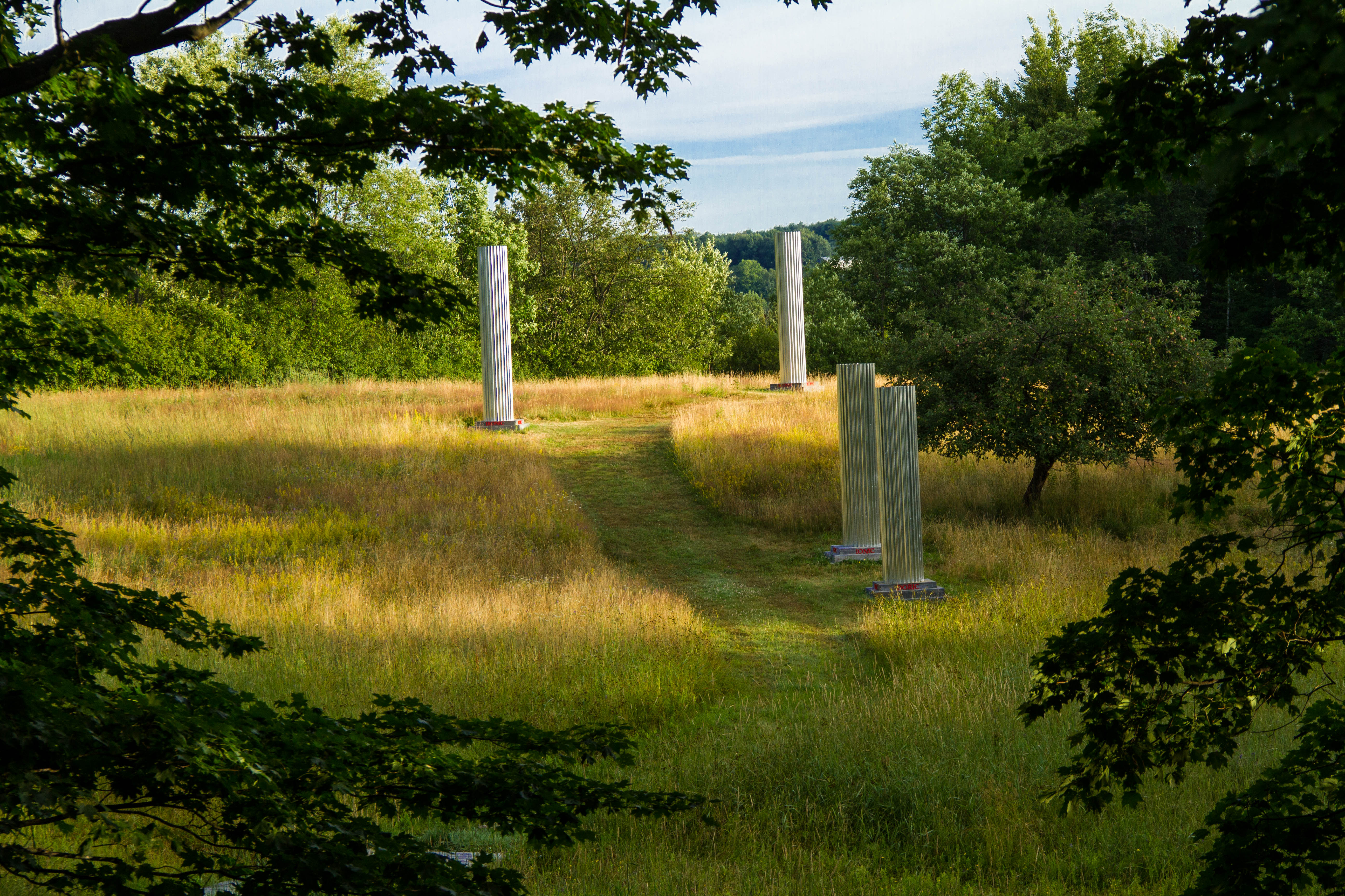 Columns of corrugated in mark a path through a field. The contemporary material connects today's world to ancient Greece. 