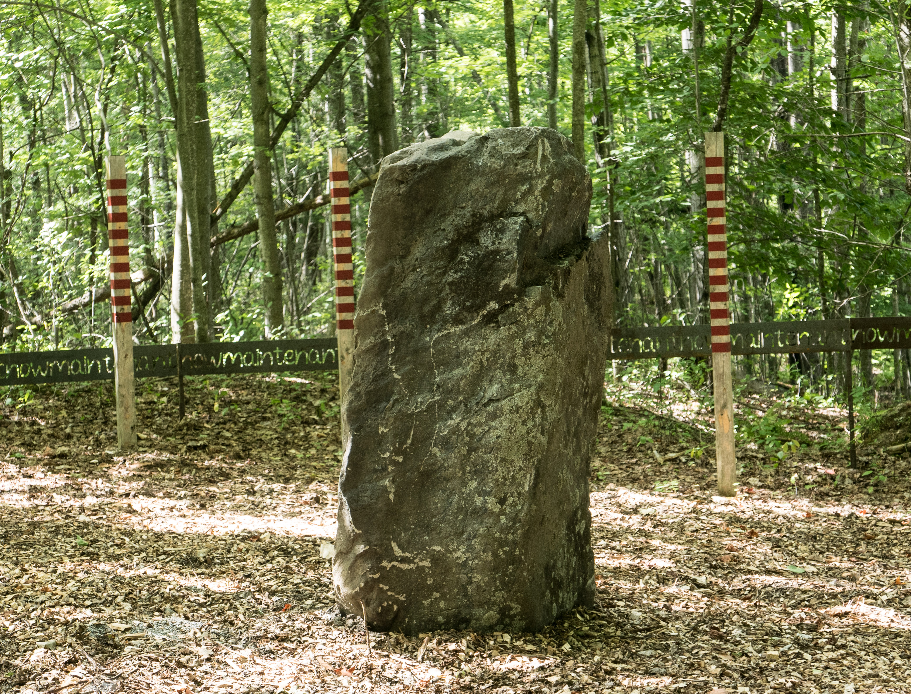 The stone stands in the middle of the clearing and its shadow marks the hour on the painted posts.
